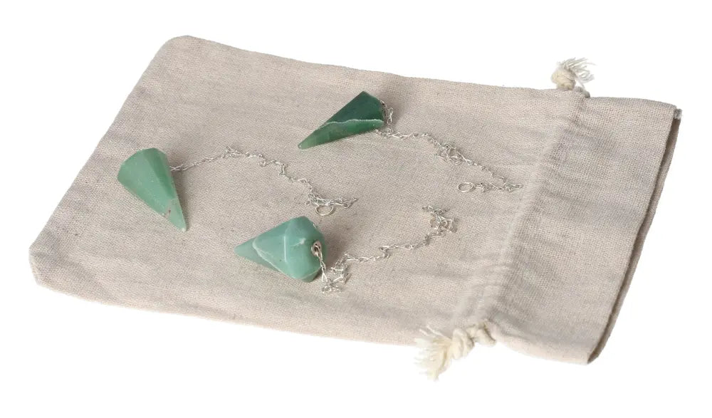 Green quartz pendulum with chain displayed on a beige cloth pouch.