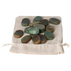 Green Quartz and Hematite thumb massagers on a cotton bag, offering relaxation and spiritual elevation from Sylvia Crystals.