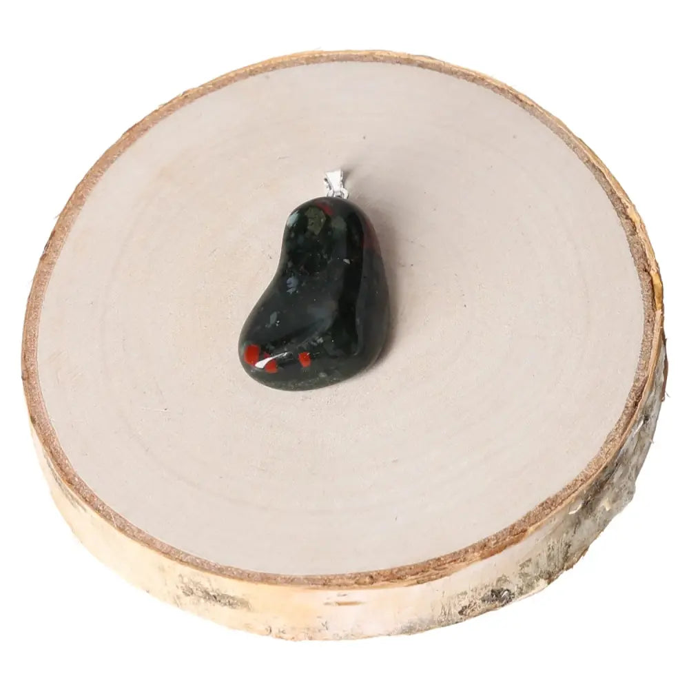 Heliortope Tumbled Pendant on wooden base showcasing vibrant hues and unique crystal character, symbol of sophistication and harmony.