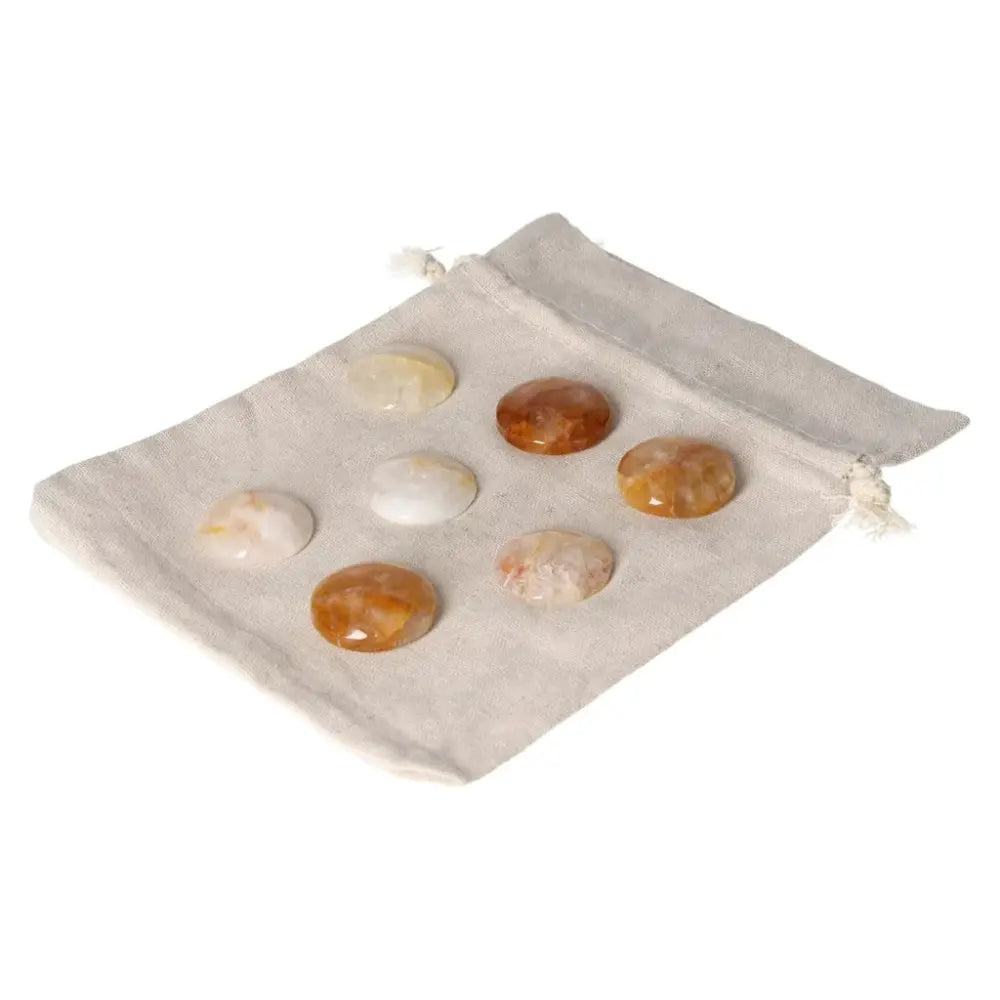 Collection of small Hematoid Quartz palmstones on a fabric pouch, featuring grounding energies and emotional balance properties.