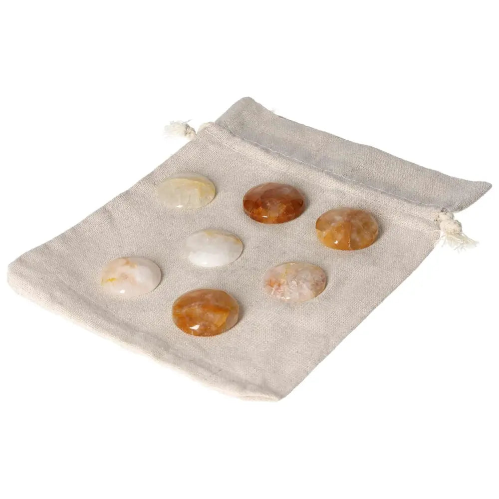Seven small Hematoid Quartz palmstones on a beige cloth pouch, ideal for grounding clarity and emotional balance with travel-friendly size.