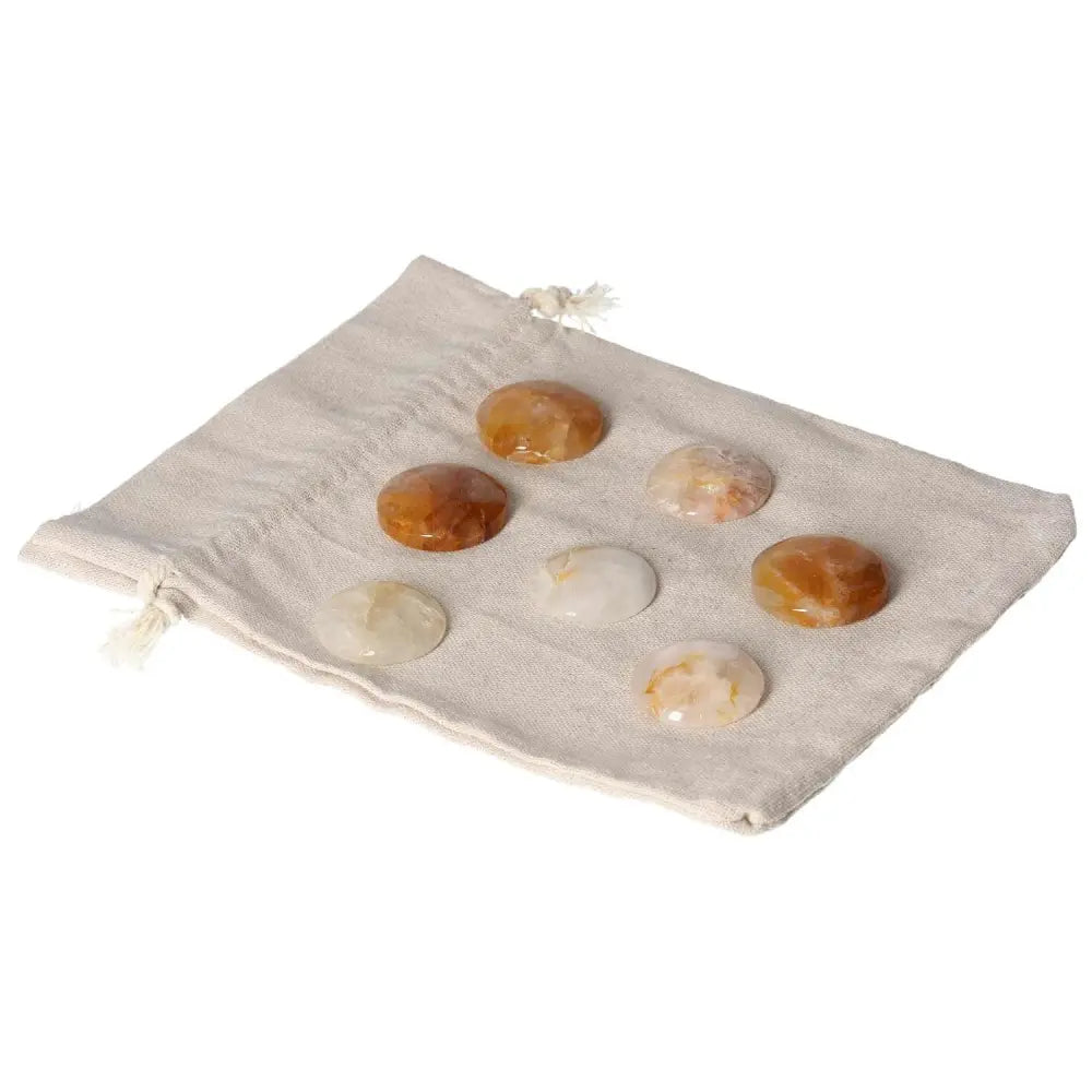 Hematoide small palmstones on a beige cloth, showcasing their grounding and clarifying properties for emotional balance and focus.