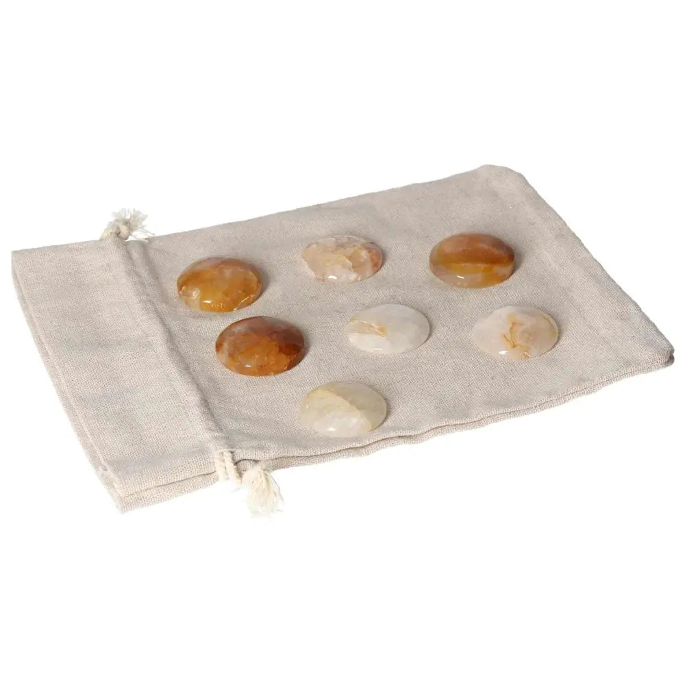 Seven Hematoid Quartz palmstones displayed on a beige cloth, showcasing their smooth texture and varying hues for emotional balance.