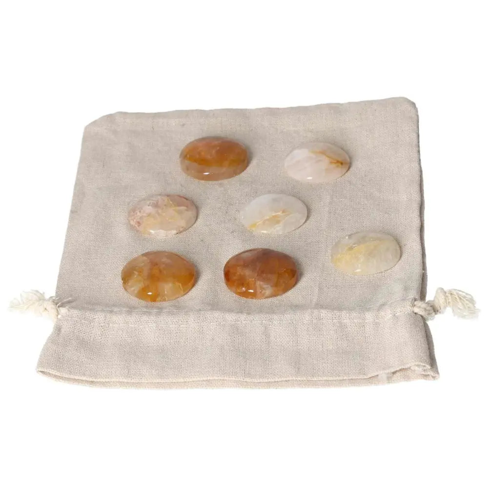 Collection of smooth Hematoid Quartz palmstones on a beige cloth, perfect for grounding clarity and emotional balance.