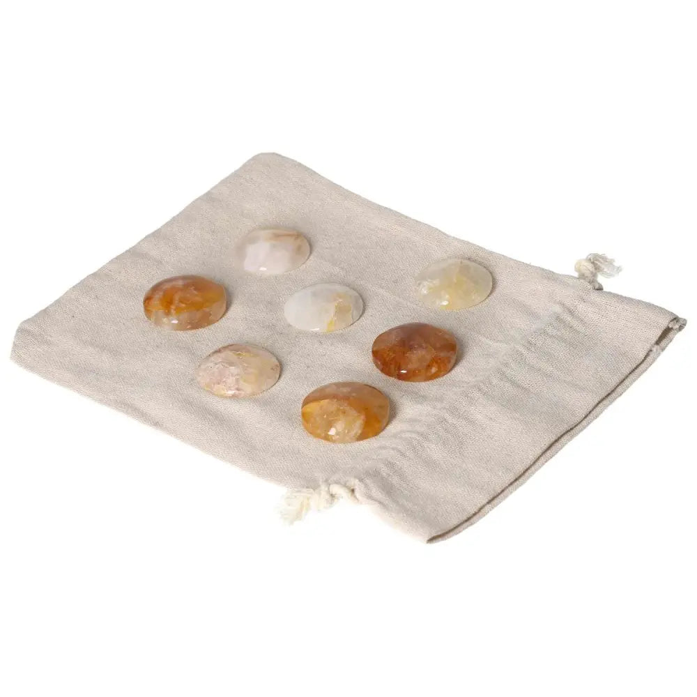 Seven Hematoid Quartz palmstones on a linen cloth, showcasing grounding and clarity properties for emotional balance and transformation.