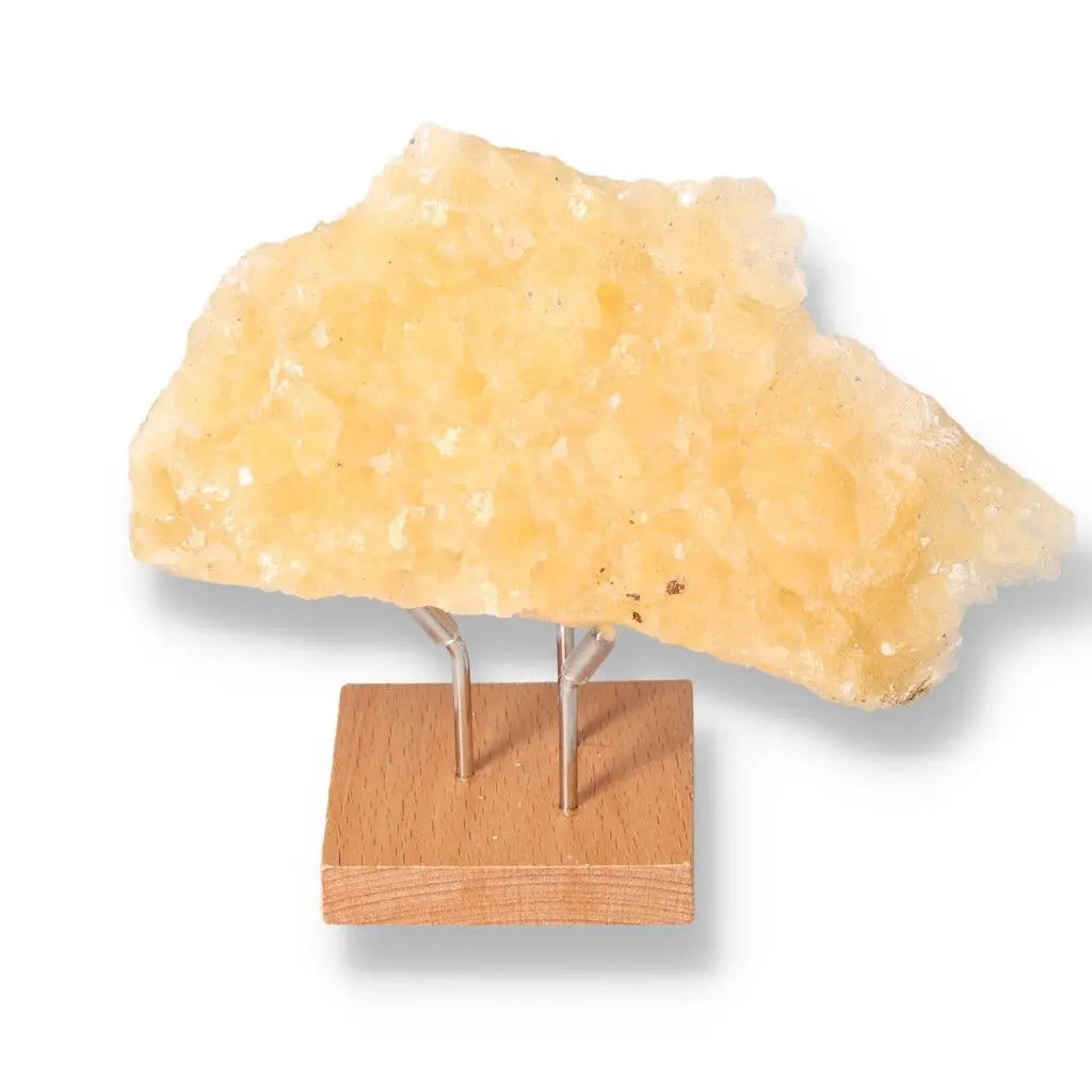 Honey Calcite stone on a wooden stand, showcasing its golden hue; boosts confidence, clarity, and motivation; aligns with solar plexus chakra.
