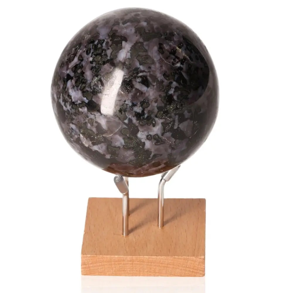 Indigo Gabbro Sphere, a stone of magic and intuition, featuring swirling black and indigo patterns on a wooden stand.