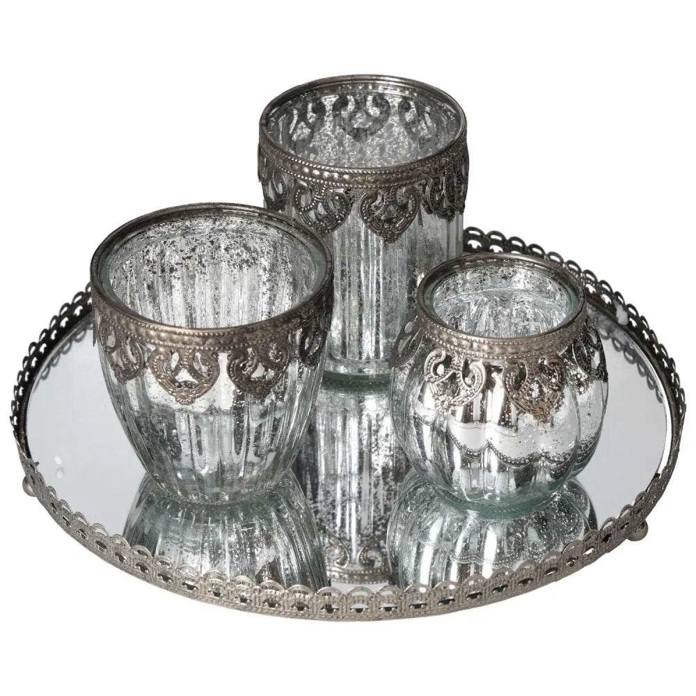 Elegant lantern set on silver mirror tray with intricate metal rim, enhancing luxurious and harmonious living spaces.