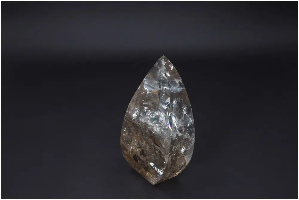 Clear Lemurian Quartz Obelisk crystal with natural clarity and balance-enhancing properties, showcasing its unique facets on a dark background.