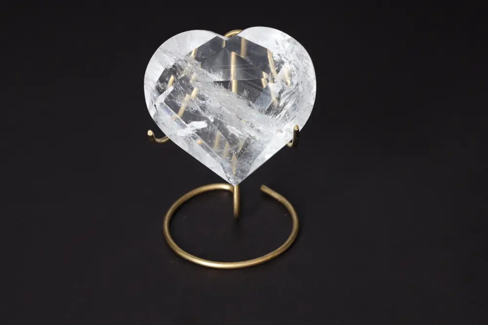 Lemurian Quartz Geometric Heart resting on a stand, showcasing its transparent, intricately carved design against a dark background.
