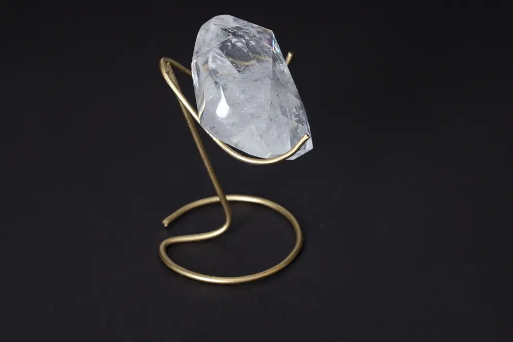 Lemurian Quartz Geometric Heart crystal elegantly displayed on a gold stand against a black background, showcasing its clarity and brilliance.