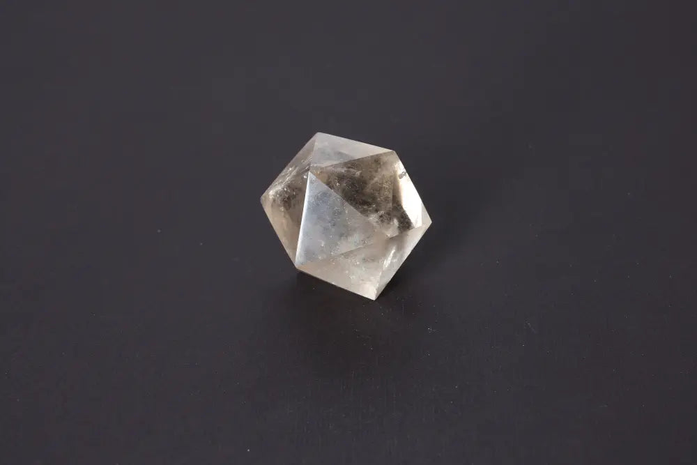 Clear geometric crystal with angular facets reflecting light on a dark background.