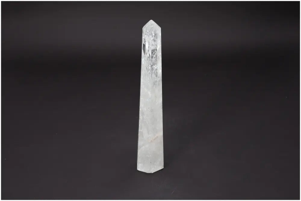 Clear Lemurian Quartz Obelisk showcasing its crystal clarity and spiritual significance on a dark background
