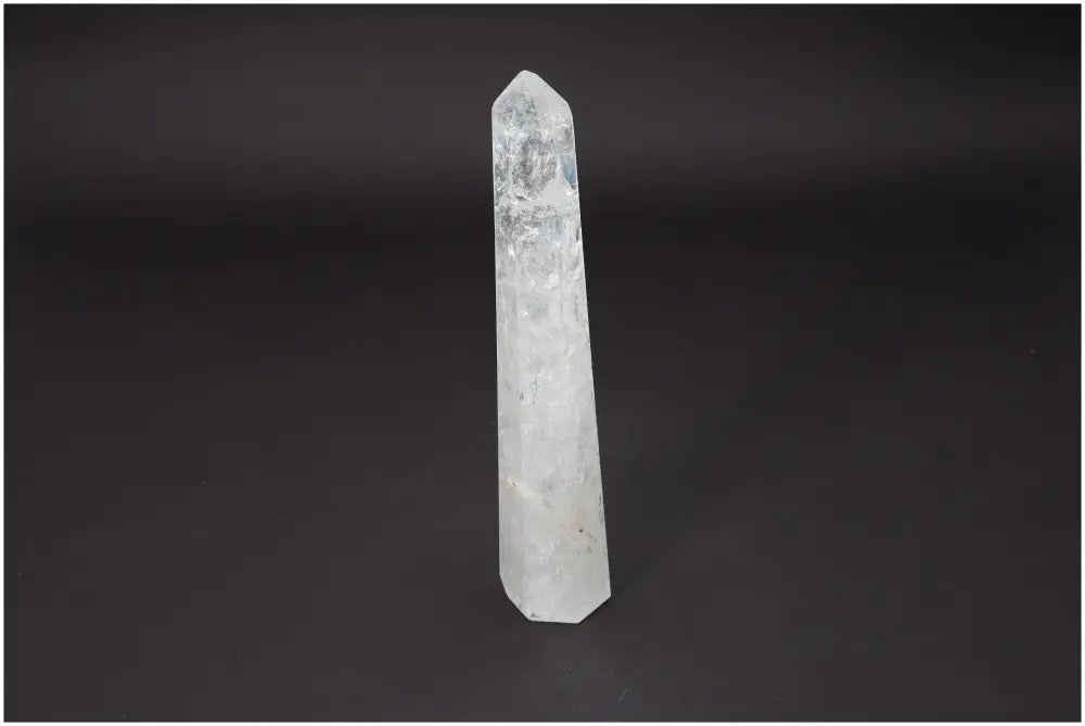 Lemurian Quartz Obelisk against a dark background, showcasing its clear crystal structure and pointed tip, ideal for spiritual rituals.