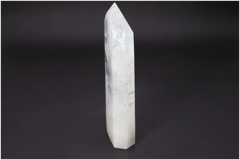 Lemurian Quartz Obelisk standing on a dark background, showcasing its translucent, pointed structure and natural inclusions.