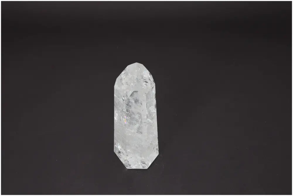 Clear Lemurian Quartz Obelisk on black background, known for its energetic and spiritual properties, associated with chakras and zodiac signs.