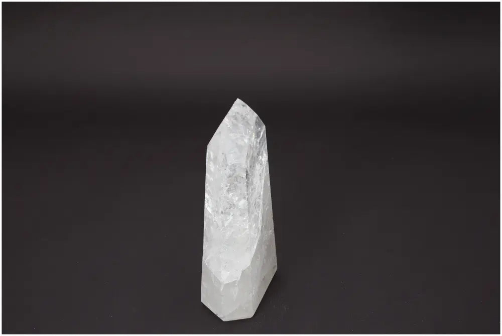 Lemurian Quartz Obelisk showcasing crystal clarity against a dark background, associated with chakras and zodiac spiritual benefits.