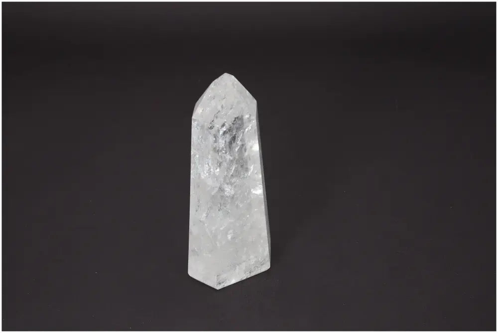 Lemurian Quartz Obelisk on dark background, showcasing clear crystalline structure, associated with chakras and zodiac signs for energy balance.