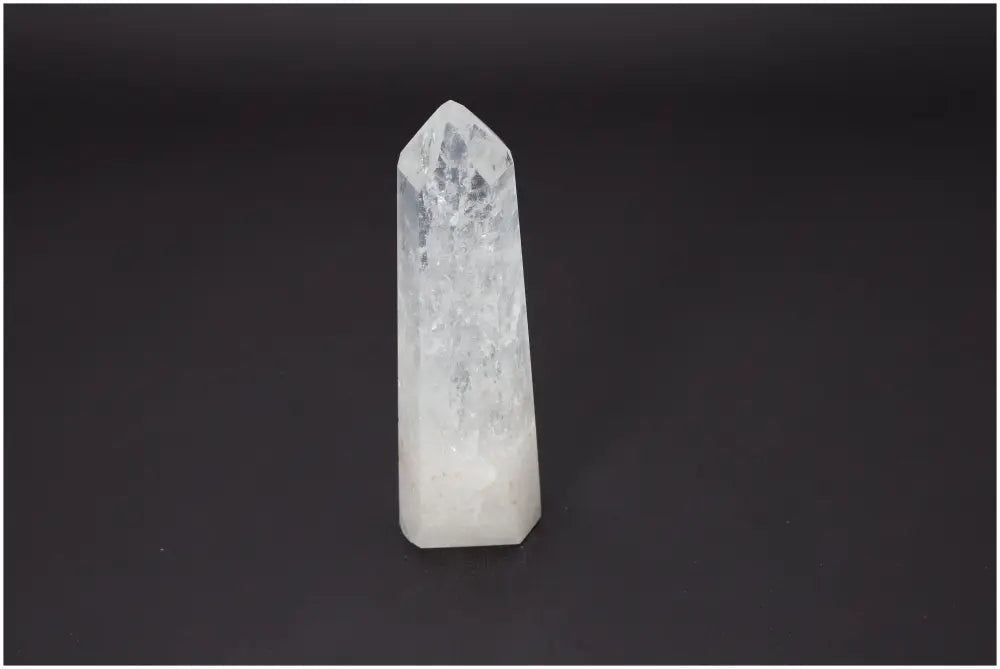 Lemurian Quartz Obelisk with healing properties, supporting chakras and zodiac signs, on a dark background.