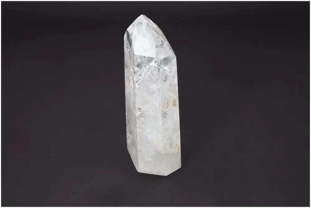 Lemurian Quartz Obelisk crystal reflecting light on a dark background, highlighting its spiritual and energetic properties for chakra healing.