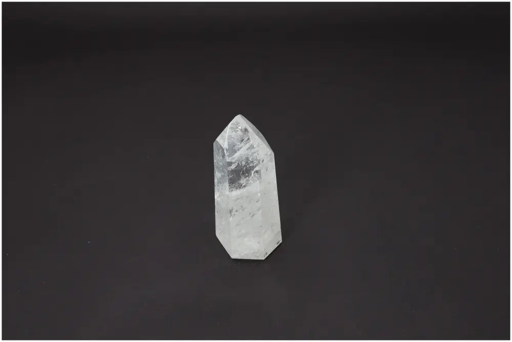 Lemurian Quartz Obelisk on black background, showcasing its natural clarity and spiritual significance for various chakras and zodiac signs.