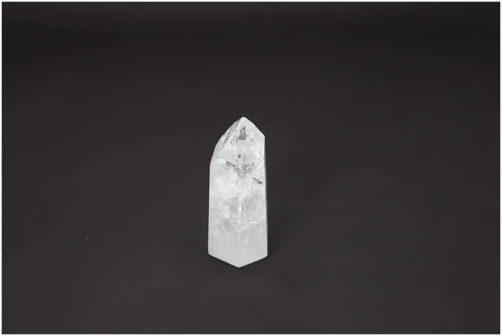 Lemurian Quartz Obelisk with spiritual and energetic properties, linked to chakras and zodiac signs, on a dark background.