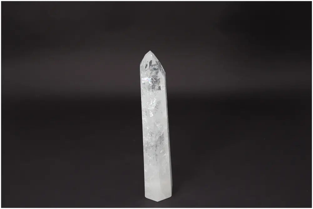 Lemurian Quartz Obelisk on dark background, clear quartz crystal known for clarity and balance, hand-selected and ethically sourced.