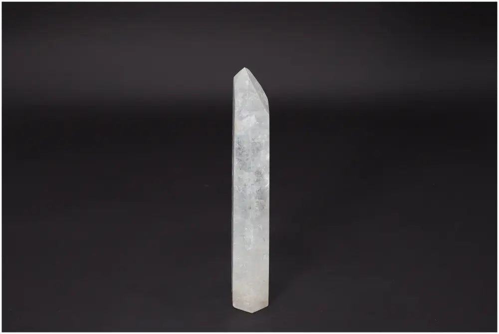 Lemurian Quartz Obelisk - clear crystal standing against dark background, symbolizing clarity and personal growth.
