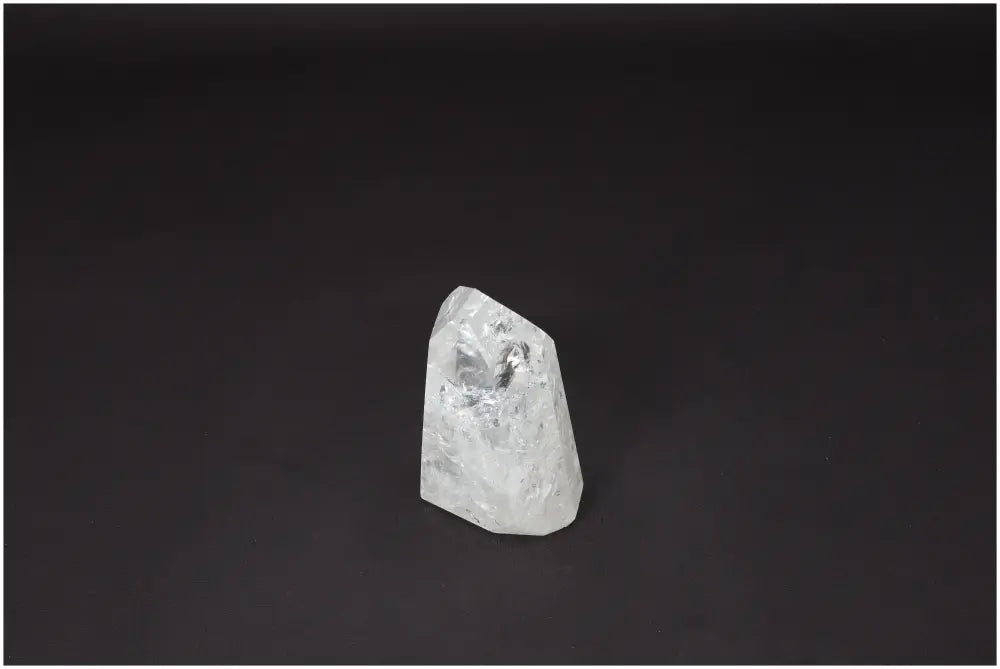 Clear Lemurian Quartz Obelisk on dark background, known for amplifying energy and promoting personal growth.