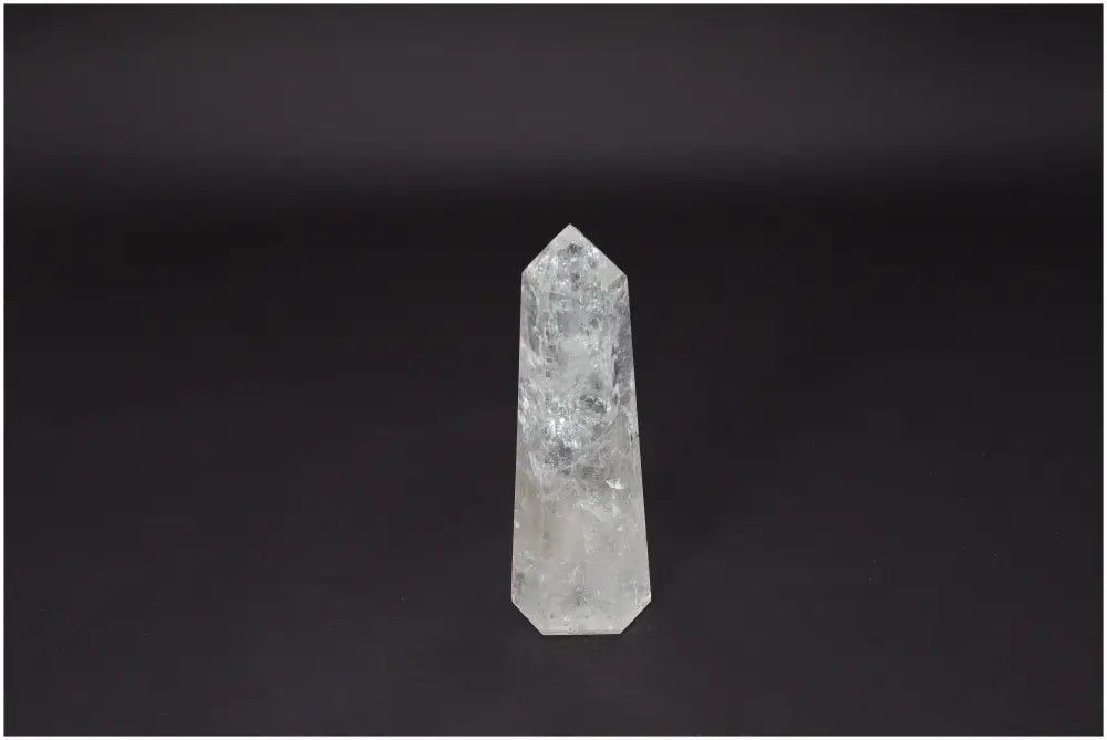 Lemurian Quartz Obelisk, clear crystal promoting clarity and balance, showcased on a dark background.