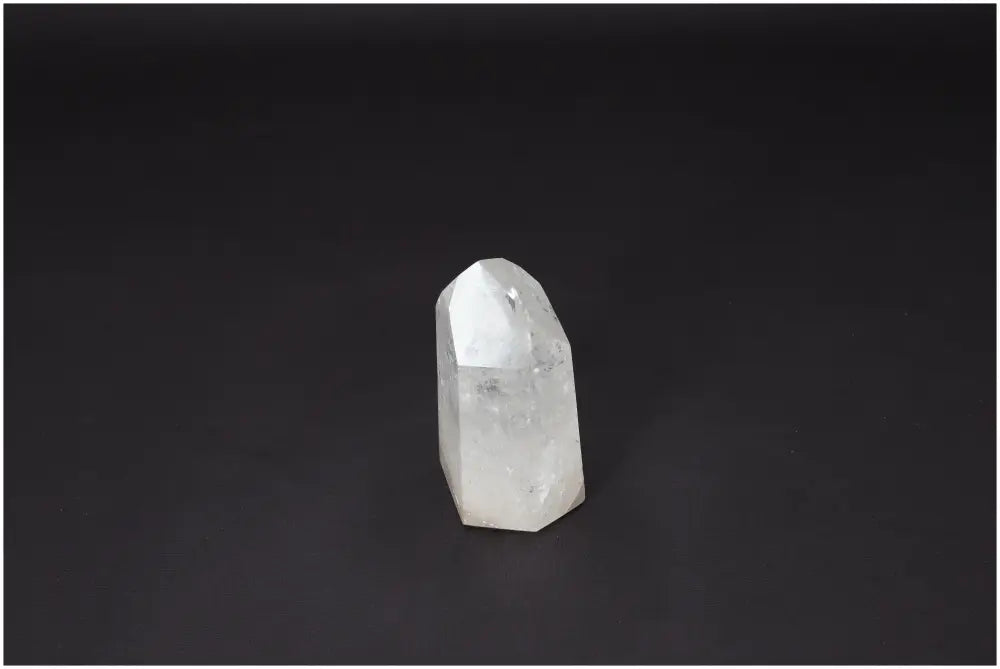 Clear Lemurian Quartz Obelisk crystal standing against a dark background, known for clarity, balance, and energy amplification.