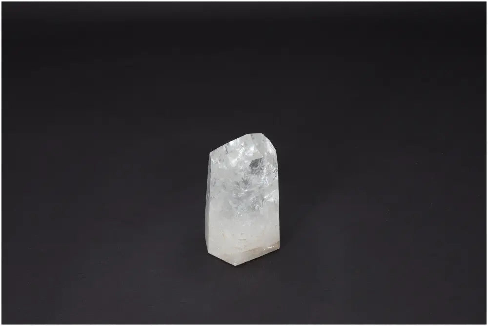 Clear Lemurian Quartz Obelisk on dark background, known as "Master Healer," amplifies energy and promotes clarity and balance.
