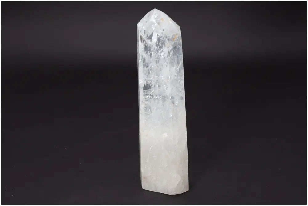 Clear Lemurian Quartz Obelisk on black background, known for its healing properties and energy amplification.