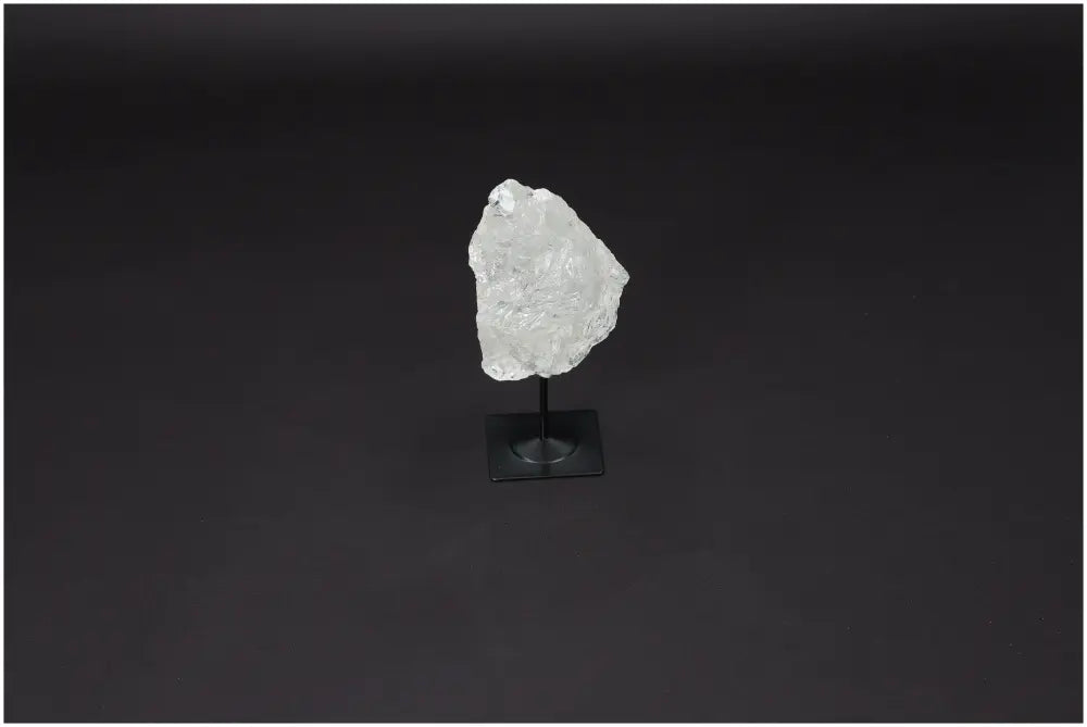 Lemurian Quartz crystal on a sleek metal stand, highlighting its natural clarity and elegance against a dark backdrop.