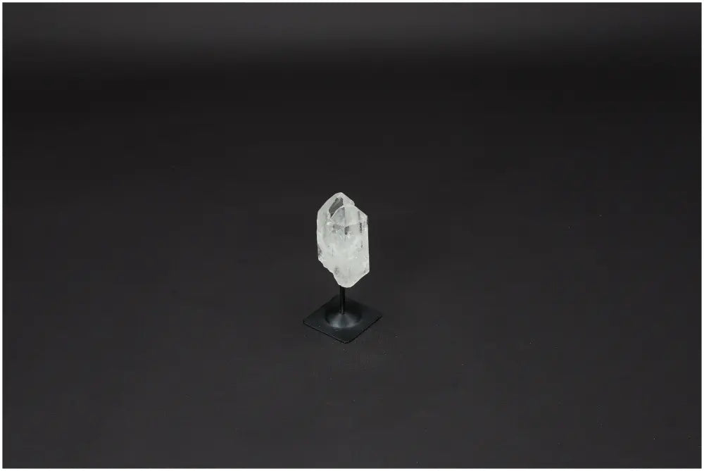Lemurian Quartz crystal on metal stand, known for clarity and balance, displayed against a dark background.