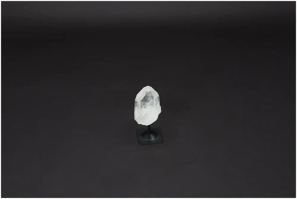 Lemurian Quartz crystal on a black metal stand, known as a Master Healer for clarity and personal growth, against a dark background.