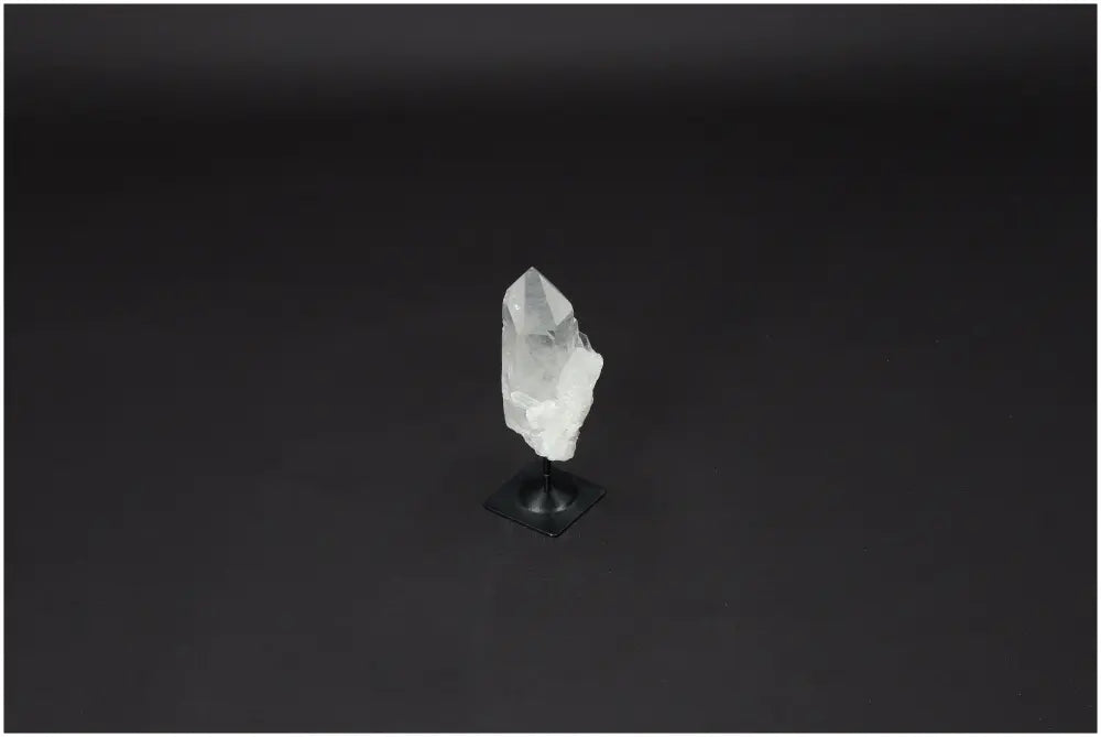 Lemurian Clear Quartz on a metal stand against a dark background, showcasing its natural clarity and healing properties.