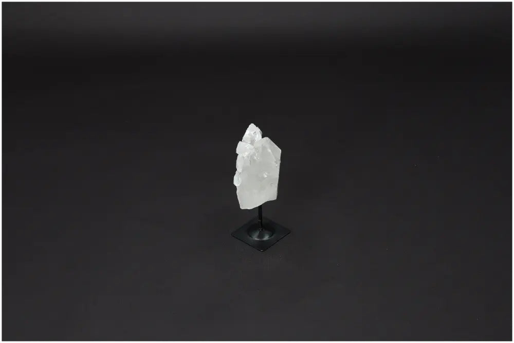 Lemurian Quartz crystal on metal stand, known for clarity and healing, set against a dark background.