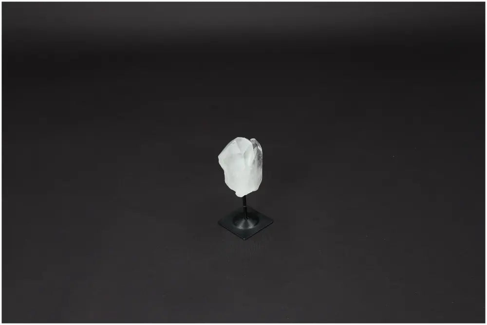Lemurian Clear Quartz stone on a metal stand, ideal for energy purification and harmonizing space, against a dark background.