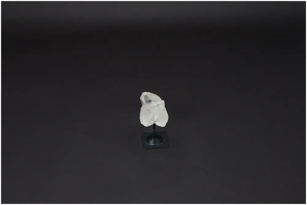 Lemurian Quartz on metal stand, a powerful clear quartz crystal known for purification and harmonizing energies, against a dark background.