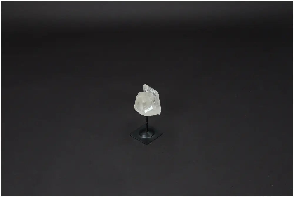 Lemurian Quartz on metal stand, a purifying crystal for balancing energy and neutralizing negative vibrations, displayed on a black background.