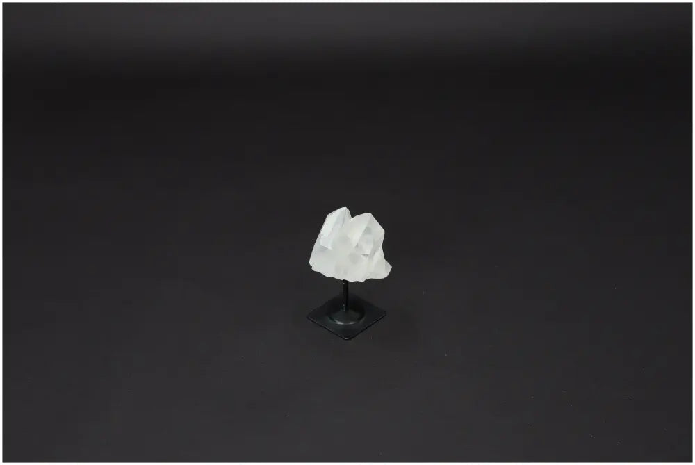 Lemurian Quartz on Metal Stand, clear quartz crystal known for purification and energy harmonizing, displayed against a dark background.