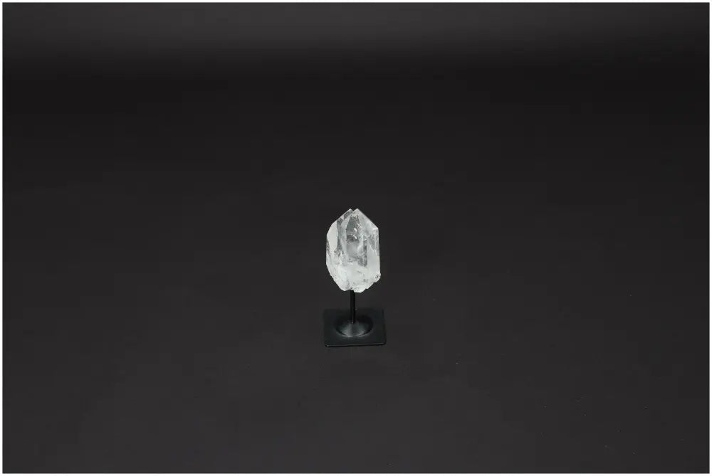 Lemurian Quartz on metal stand, a powerful clear quartz crystal for purification and harmonizing energy, shown against a dark background.