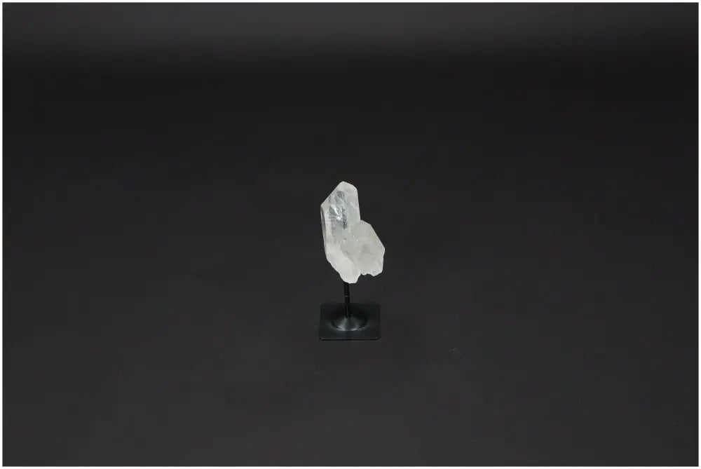 Lemurian Clear Quartz on metal stand against dark background, known for purification, harmonizing energy, and neutralizing negativity.