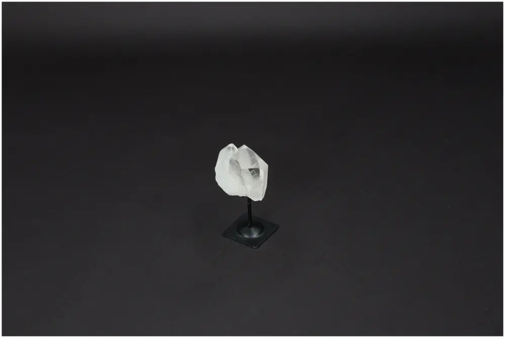 Lemurian Clear Quartz on metal stand against black background, a purifier of negative energy and harmonizer of body, mind, and space.