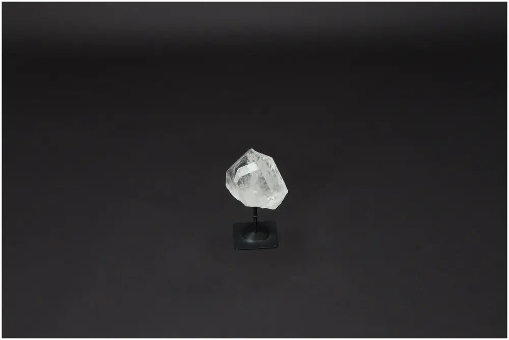Lemurian Quartz stone on a metal stand against a black background, showcasing its clear, purifying properties.