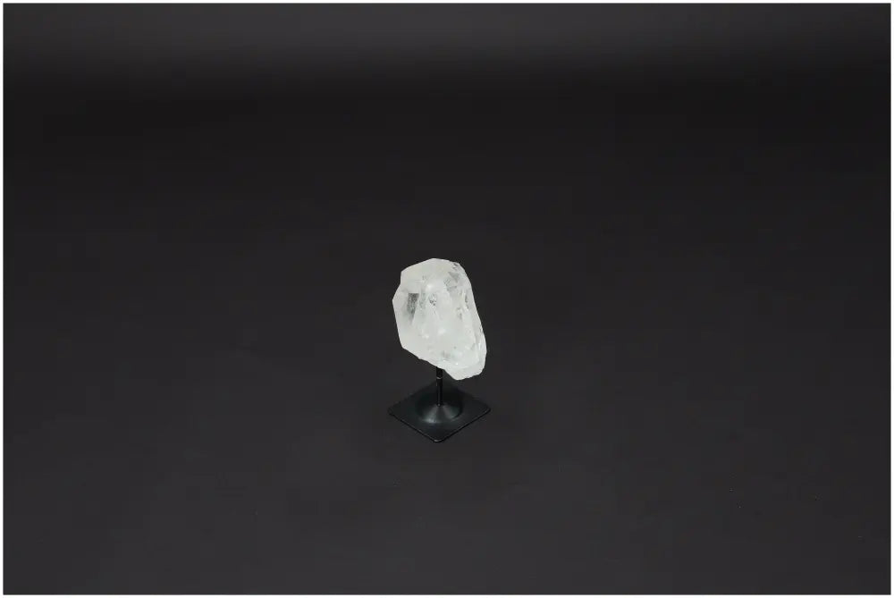 Lemurian Quartz crystal on metal stand for purification, harmonizing energy, and absorbing negative vibrations, against a dark background.