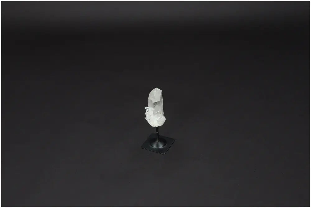 Lemurian Clear Quartz on metal stand, known for purifying and harmonizing energy, against a dark background.