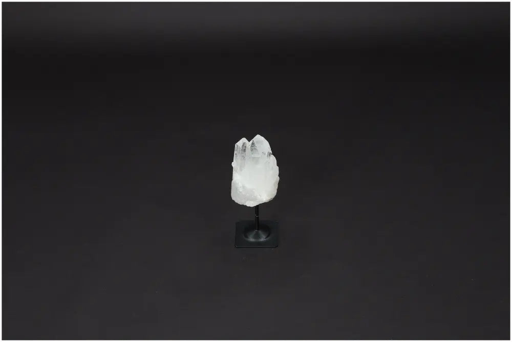 Lemurian Clear Quartz on a black metal stand against a dark background, known for its purification and energy harmonizing properties.