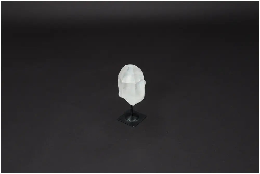 Lemurian Quartz on metal stand against dark background, showcasing clear quartz crystal with properties of purification and electromagnetic neutralization.